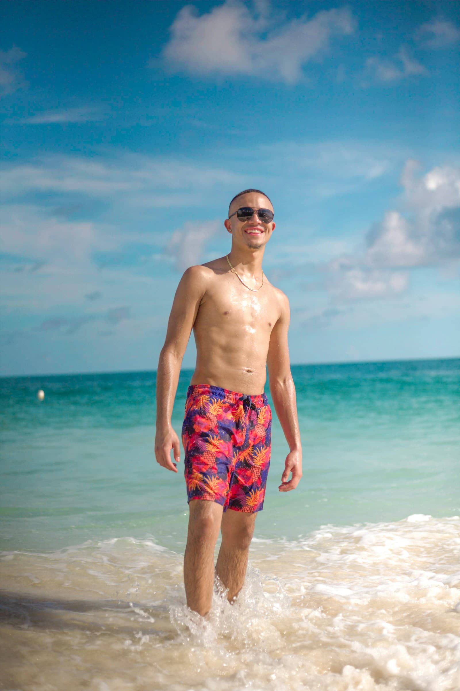 A smiling man standing in shallow turquoise water in The Bahamas